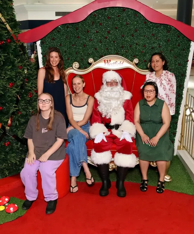 People taking a picture around Santa Claus